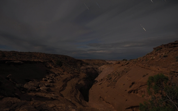 Red canyons are illuminated under the night sky